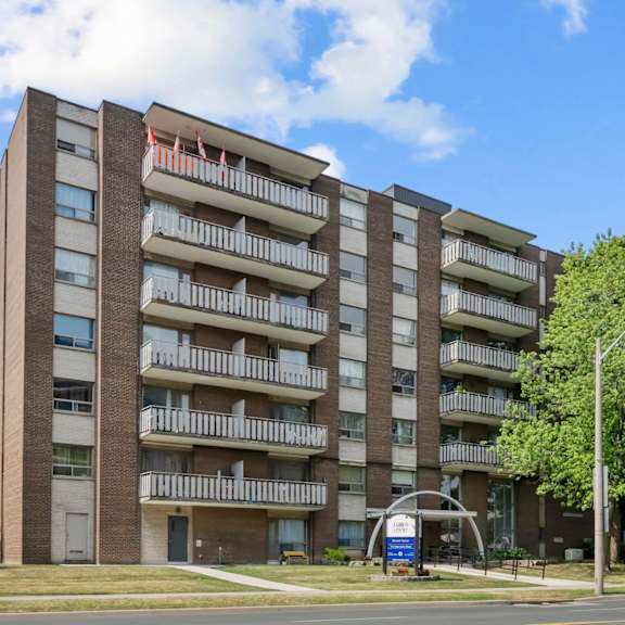 a tall apartment building with balconies and a blue sign in front.