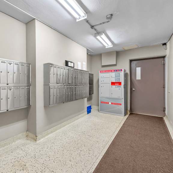 a hallway with a row of lockers on the left and a door on the right.