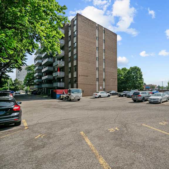 a parking lot with cars and a tall building in the background.