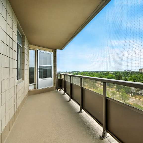 a balcony with a view of a parking lot and trees.