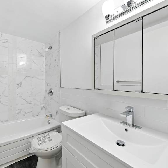 a white bathroom with a marble wall and a toilet paper roll.