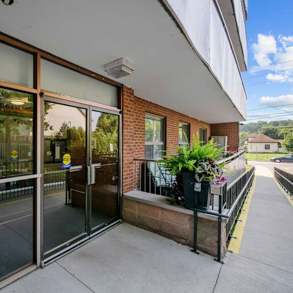 a building with a glass door entrance and a balcony with potted plants.
