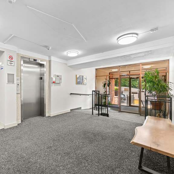 a hallway with a green exit sign and a bench.