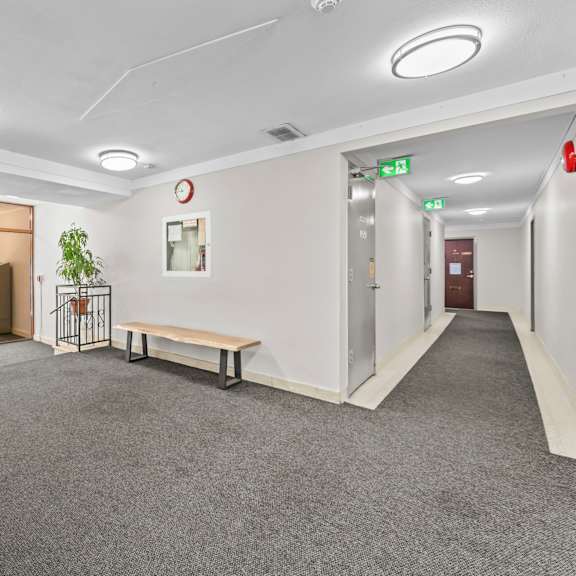 a long hallway with a bench and a fire extinguisher.