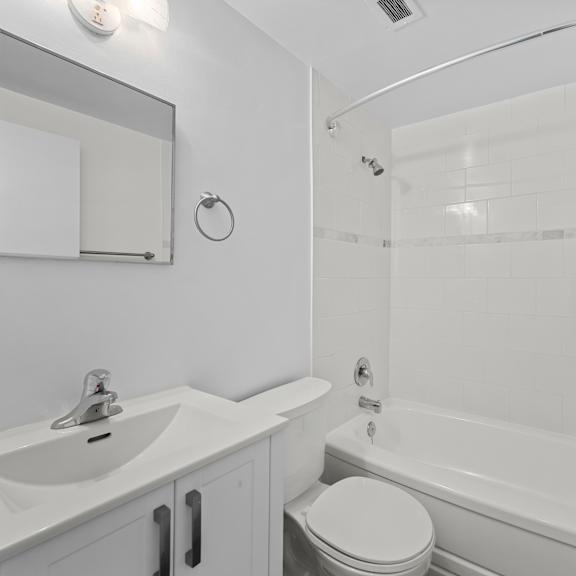 a white bathroom with a toilet, sink, and bathtub.