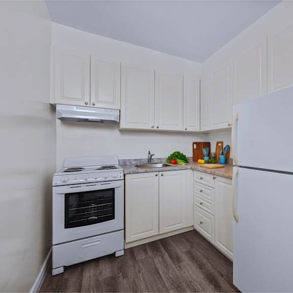 a white kitchen with a fridge, stove and cupboards.