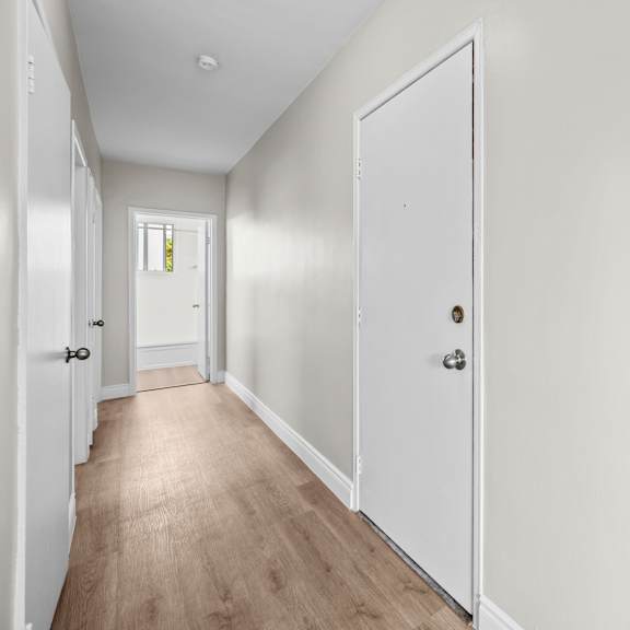 a long white hallway with a white door on the right.