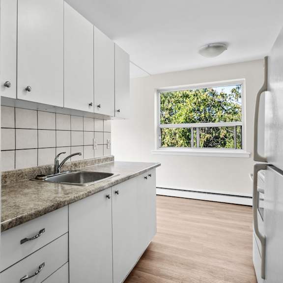 a kitchen with white cabinets and a window.