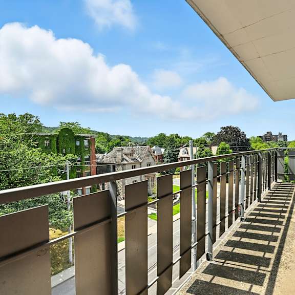 a balcony with metal railings overlooks a lush green landscape.