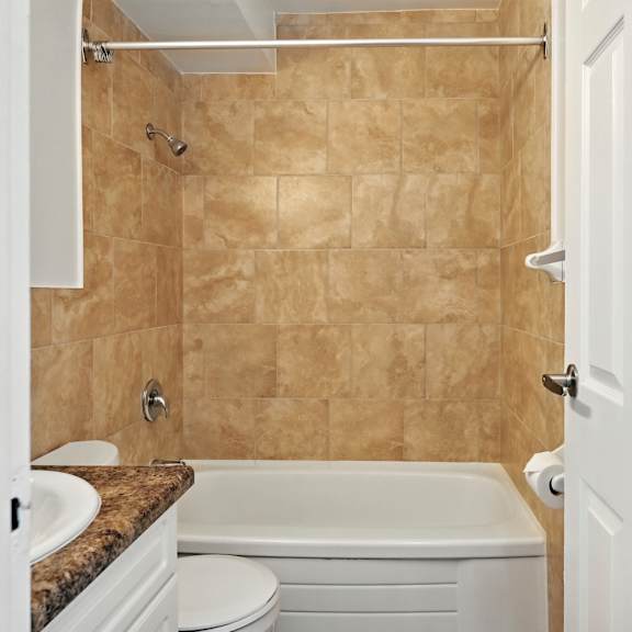 a bathroom with a beige tile shower and white fixtures.