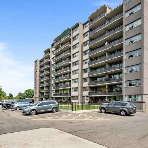 a tall apartment building with a parking lot in front.
