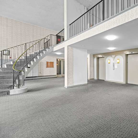 a spacious room with a staircase and two doors.