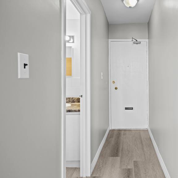 a white door with a black handle is in the middle of a hallway.