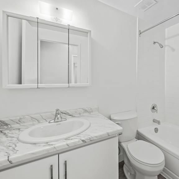 a white bathroom with a marble countertop and a toilet.