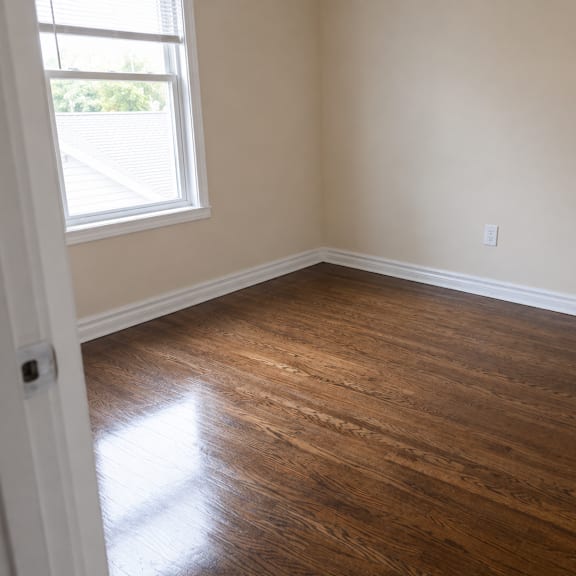 a room with wooden flooring and a window letting in natural light.