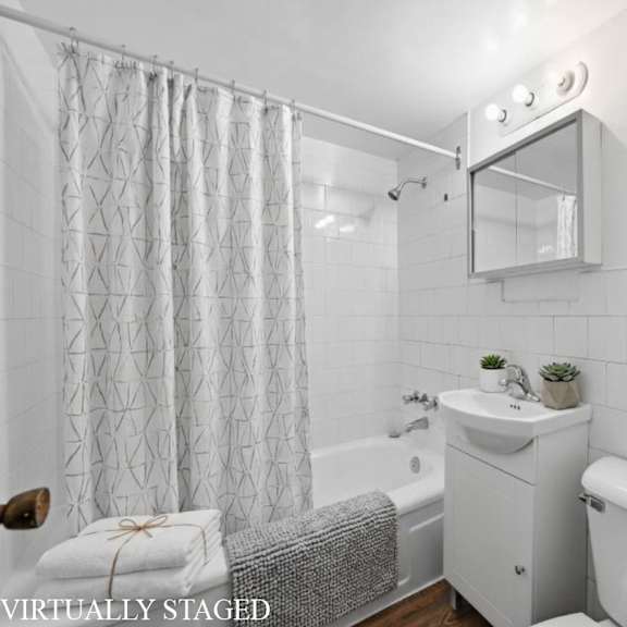 a white bathroom with a tub, sink, and mirror.