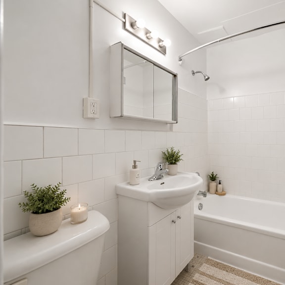 a white bathroom with a tub, sink, and mirror.