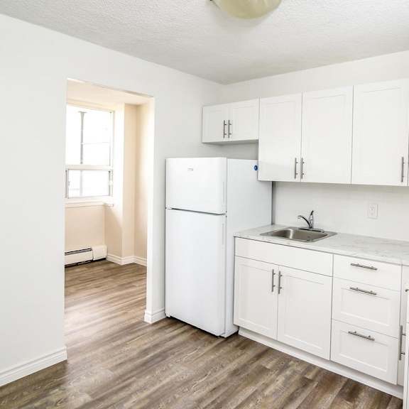 a kitchen with white cabinets and a marble countertop.