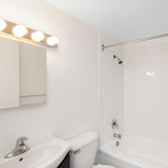 a white bathroom with a sink, toilet, and bathtub.