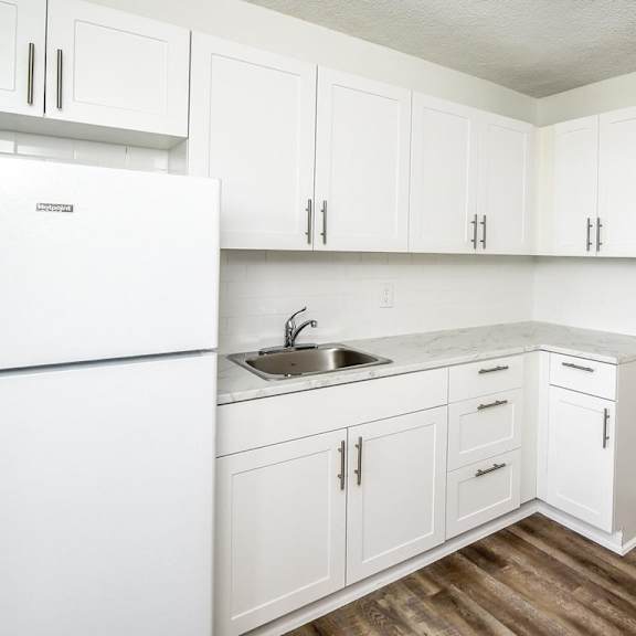 a kitchen with white cabinets and a white fridge.