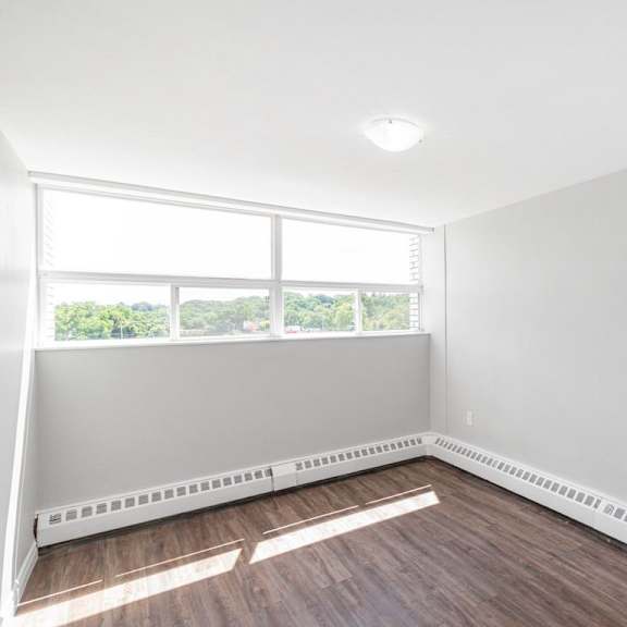 a room with white walls and a window with a view of trees outside.
