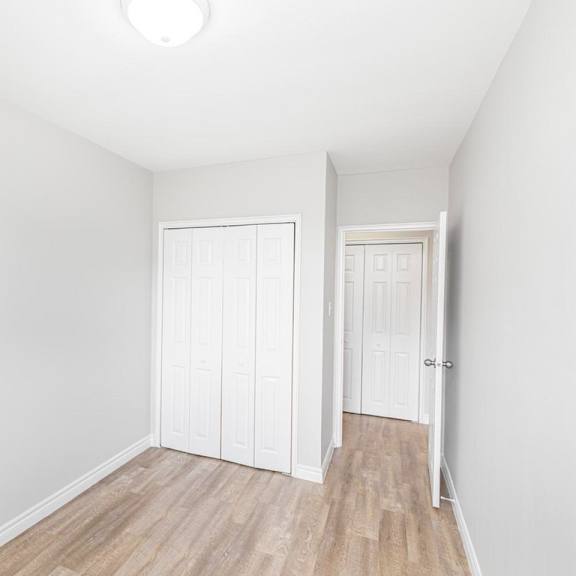 a white bedroom with a wood floor and two closets.