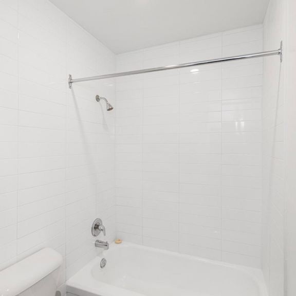 a white bathroom with a tub, toilet, and shower.