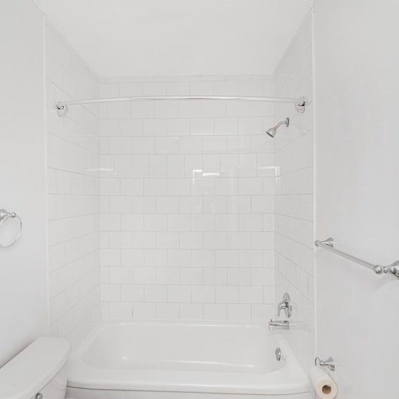 a white bathroom with a tub and toilet.