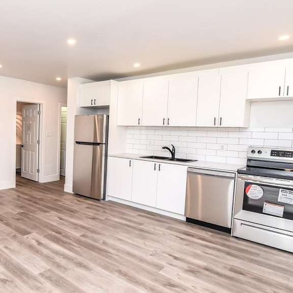 a kitchen with white cabinets and a wooden floor.