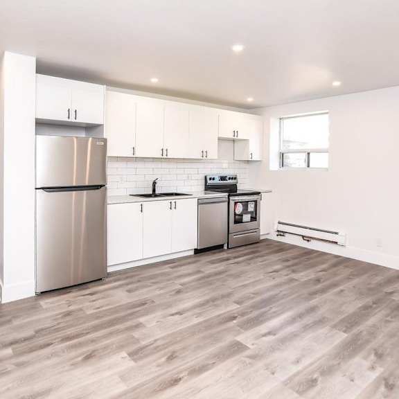 a kitchen with white cabinets and a wooden floor.