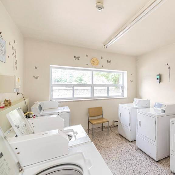 a laundromat with washers and dryers and a window.