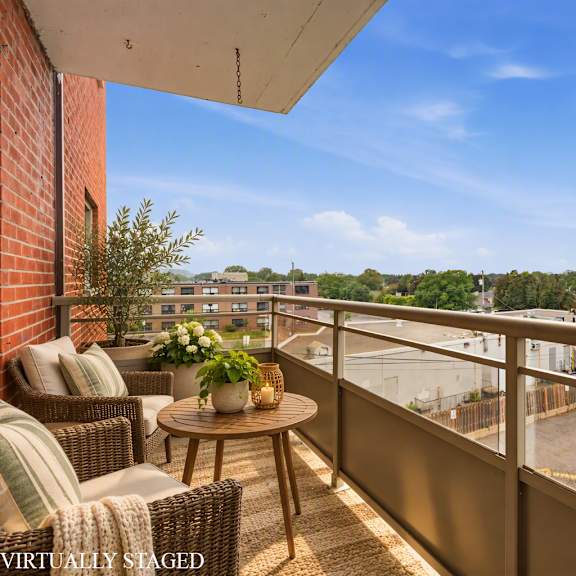 balcony with a table and chairs overlooking a parking lot.