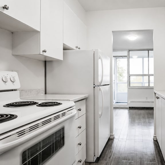 a white kitchen with a stove, refrigerator, and sink.