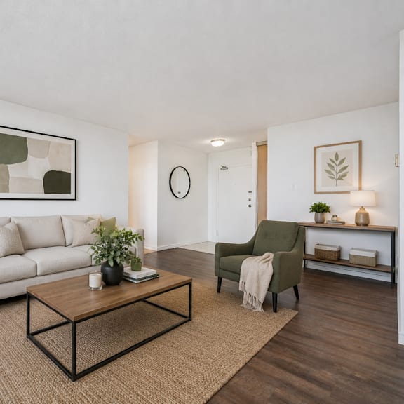 a living room with a white couch, a green chair, and a brown rug.