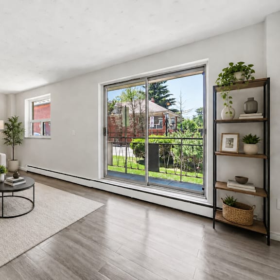 a living room with a white couch, a coffee table, and a large window with a view of a backyard.