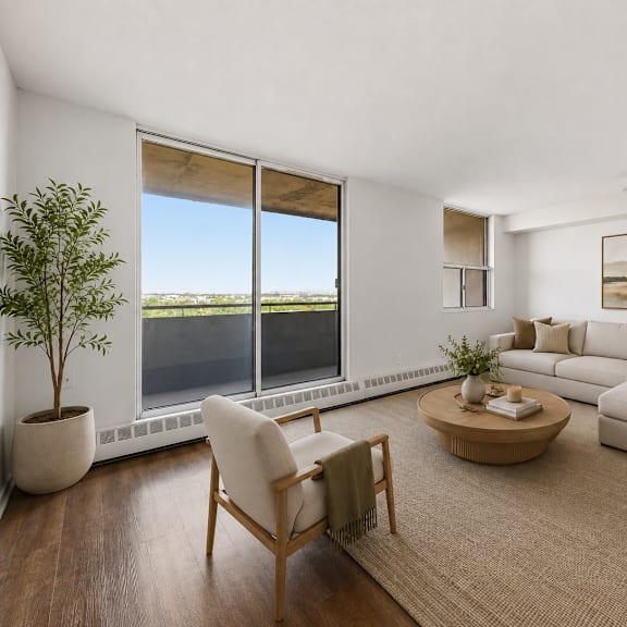 a living room with a large window, a sofa, a chair, a coffee table, and a potted plant.