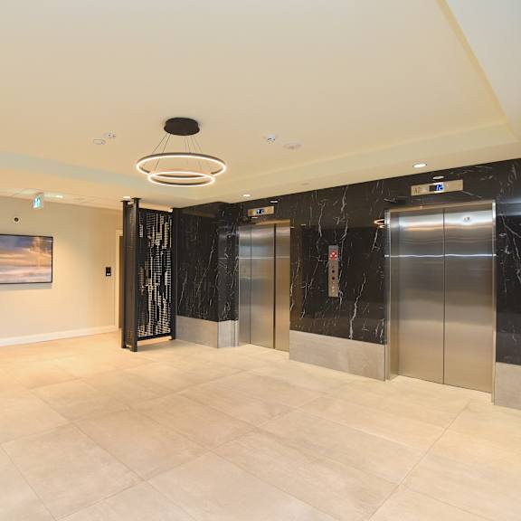 a spacious lobby with marble floors and a modern art piece on the wall at roxy apartments, ontario