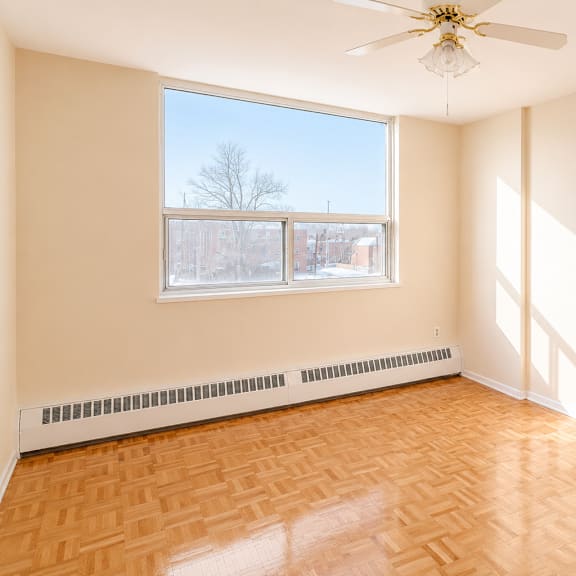 a room with a ceiling fan and a window showing a view of a tree.