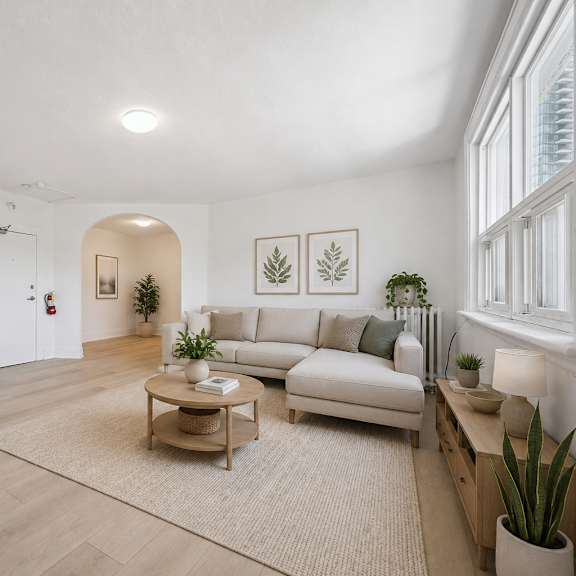 a living room with a couch, coffee table, and plants.