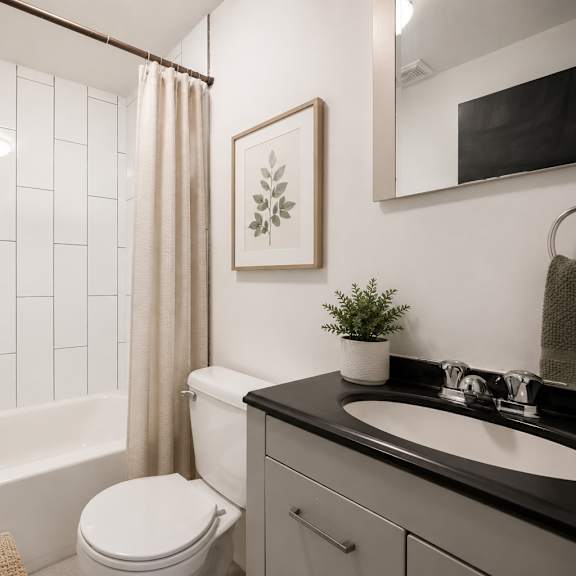 a bathroom with a white toilet, a black sink, and a white bathtub.