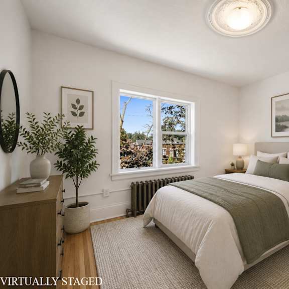 a bedroom with a large bed and a window overlooking a tree.
