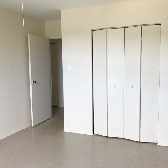 a room with a white door and a white closet with four doors.