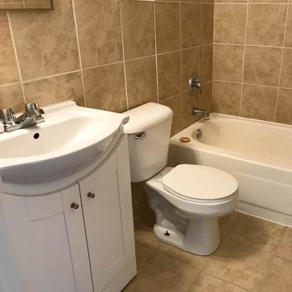 a white toilet sits next to a sink in a tiled bathroom.