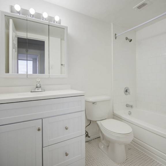 a white bathroom with a toilet, sink, and mirror.