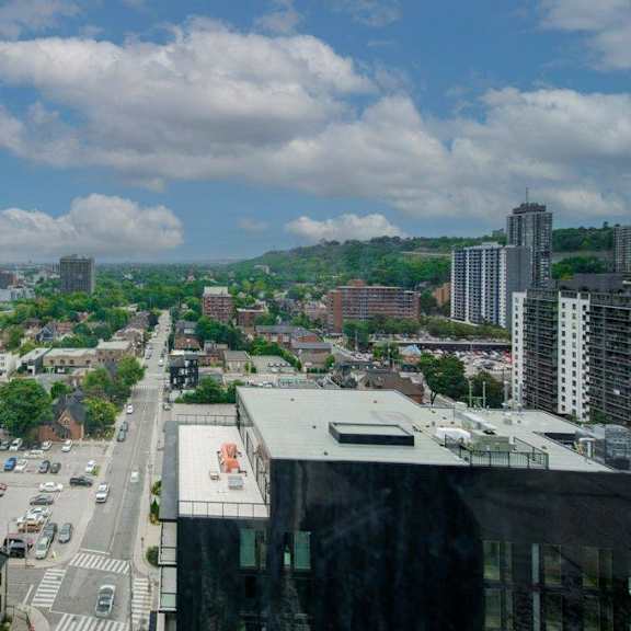a cityscape with buildings, roads, and cars under a partly cloudy sky.