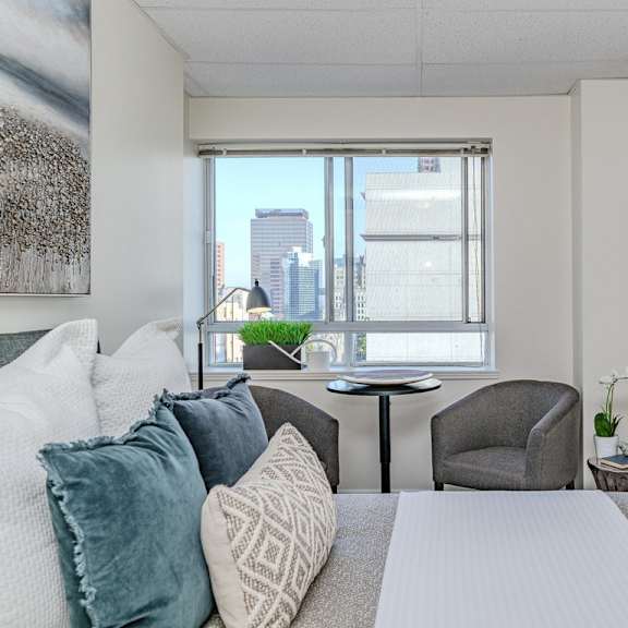a well-lit bedroom with a large bed and a city view through the window.