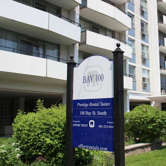 a sign for bay 100 apartments stands in front of a white building.