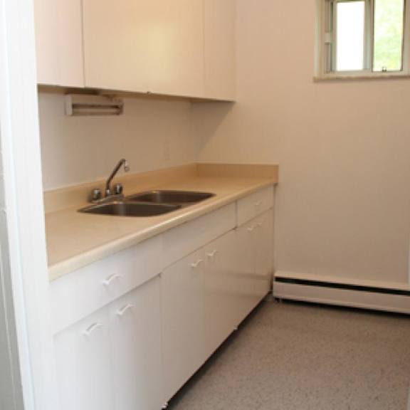 a kitchen with white cabinets and a window.