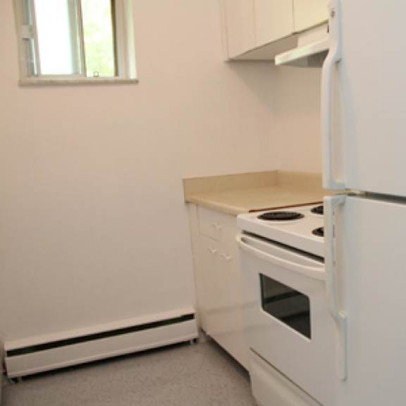 a white kitchen with a stove and refrigerator.