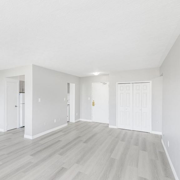 a spacious room with white walls and wooden flooring.